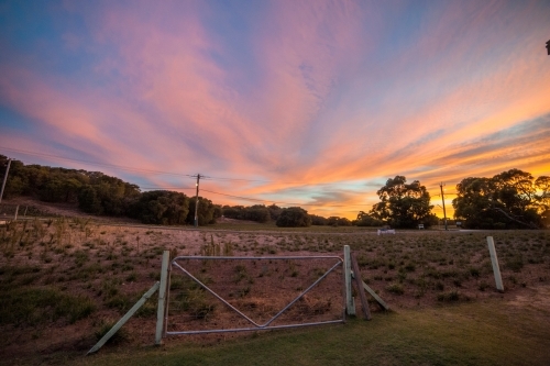 Farming gate in front of the coloured sunset sky. - Australian Stock Image