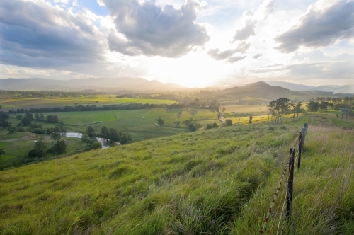 Farmland vista with fence looking into the light - Australian Stock Image