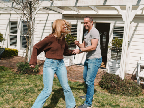Father and daughter enjoying playful moment outside modern home entrance - Australian Stock Image