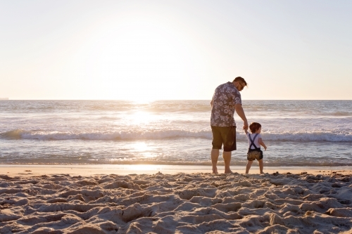 Father And Daughter Holding Hands On the Beach At Sunset - Australian Stock Image