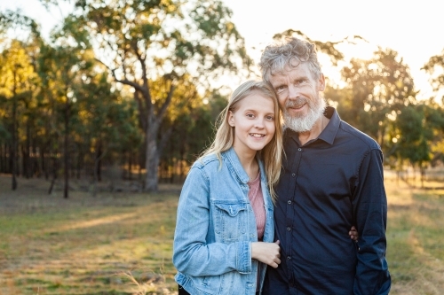 Father and daughter hug together in paddock with copy space - Australian Stock Image