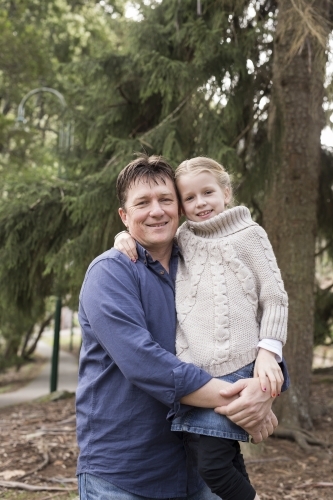 Father and daughter hugging outdoors - Australian Stock Image