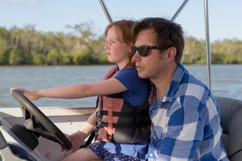 Father and daughter steering a boat