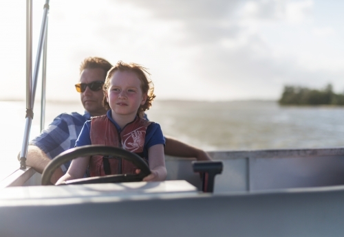 Father and daughter steering a boat together