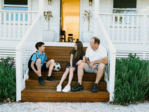 Father and his children sitting on the porch wooden steps. - Australian Stock Image