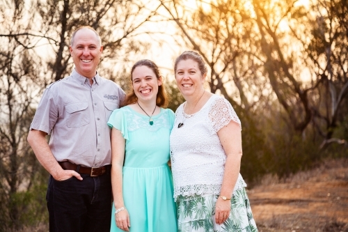 Father and mother stand with their daughter in smokey sunset light - Australian Stock Image