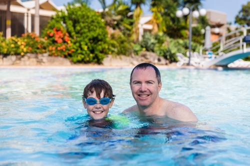 Father and son happy smiling in pool on holidays - Australian Stock Image