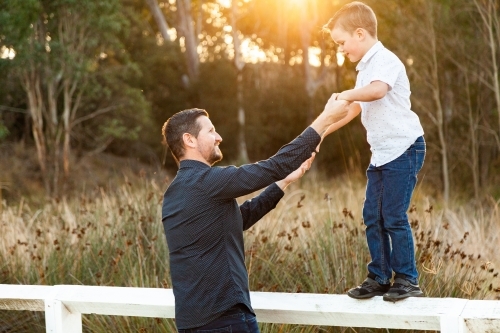 Father and Son holding hands balancing on the fence