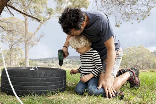Father and son making a tyre swing in country backyard - Australian Stock Image