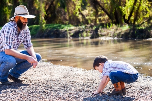 Father and son play beside river - Australian Stock Image