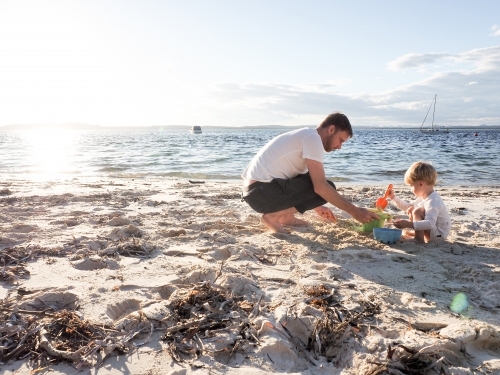 Father and son playing at the beach at sunset