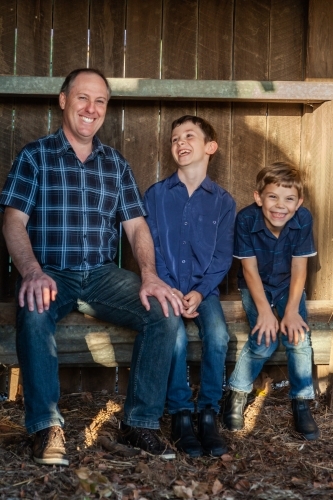 Father and sons sitting together in rural country setting - Australian Stock Image