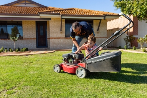 father and toddler with lawnmower - Australian Stock Image