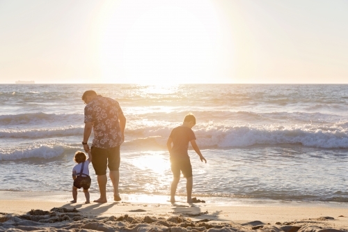 Father and Two Children Playing On the Shoreline At Sunset