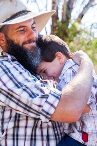 Father and young son hugging outside - Australian Stock Image