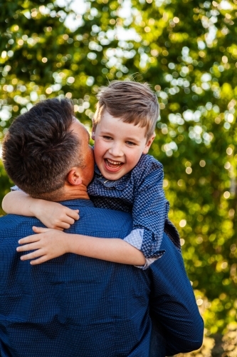 Father and young son laugh together and hug outside - Australian Stock Image
