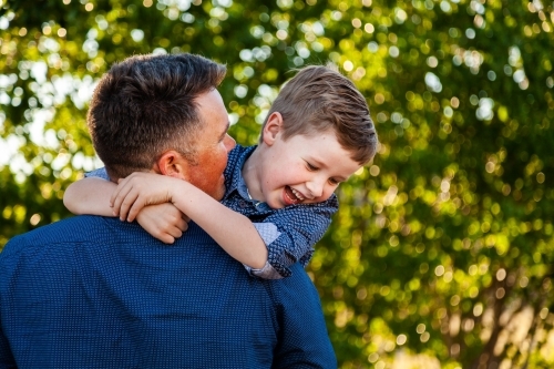 Father and young son laugh together and hug outside