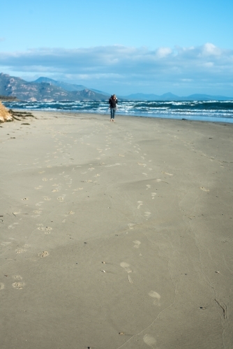 Father carrying son on his back along beach - Australian Stock Image