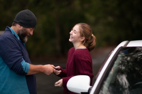 Father handing car keys to teenaged daughter - Australian Stock Image