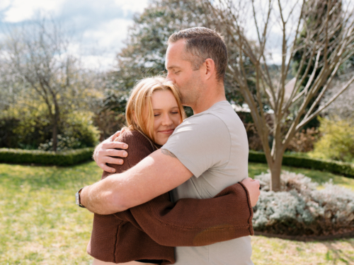 Father hugging teenage daughter in the garden and giving her a kiss in the forehead - Australian Stock Image