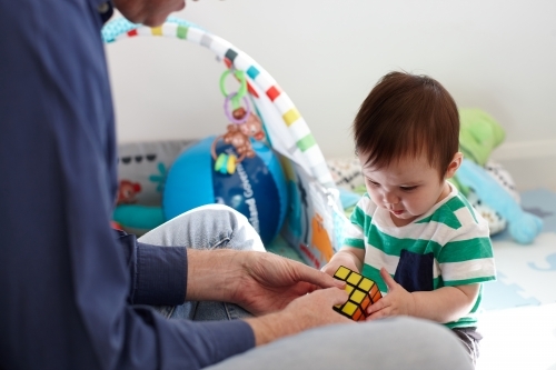 Father playing with baby boy in living room - Australian Stock Image