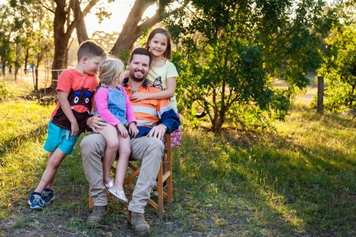 Father relaxing with three of his kids outside - Australian Stock Image