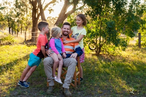 Father relaxing with three of his kids outside - Australian Stock Image