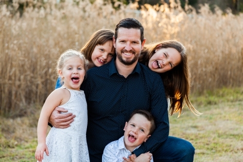 Father smiling of portrait with his four happy children - Australian Stock Image