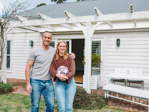 Father stands close with teenage daughter with his arms over her shoulder - Australian Stock Image