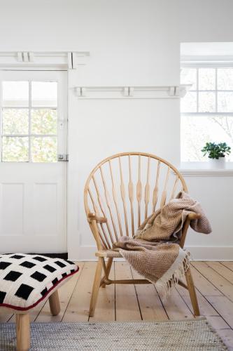 Feature wooden arm chair with throw and cushion ottoman in modern designer apartment - Australian Stock Image