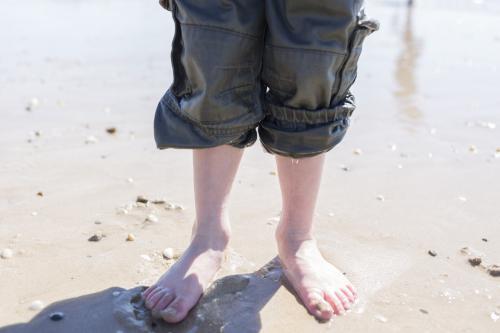Feet of a young boy with wet pants at the beach - Australian Stock Image