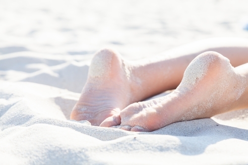 Feet of person relaxing in beach sand - Australian Stock Image