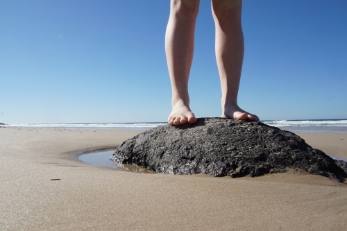 Feet standing on rock at beach