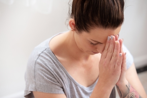 female bow hands to third eye yoga meditation pose in studio - Australian Stock Image