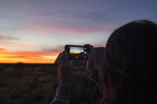 Female capturing a photo of sunrise at Uluru-Kata Tjuta National Park - Australian Stock Image