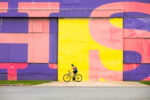 Female cyclist in front of bright coloured wall
