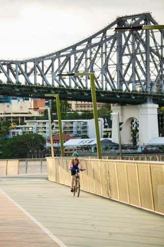 Female Cyclist Riding with Story Bridge Behind - Australian Stock Image