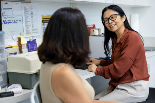 Female doctor having conversation with senior woman at clinic - Australian Stock Image