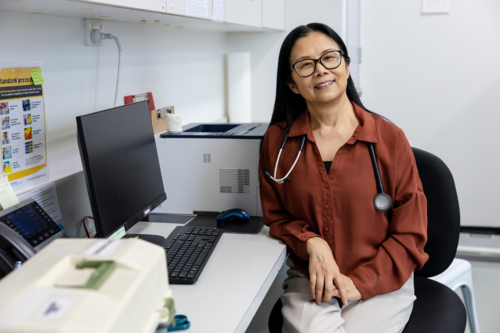 Female doctor sitting behind her desk inside exam room - Australian Stock Image
