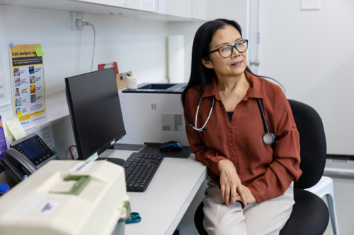 Female doctor sitting behind her desk inside exam room - Australian Stock Image