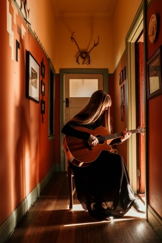 Female guitarist plays in beautiful light.
