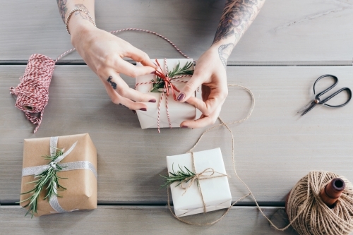 Female hands tying bows on stylishly wrapped Christmas gifts