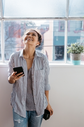 Female in casual clothes laughing with her head tilted back - Australian Stock Image