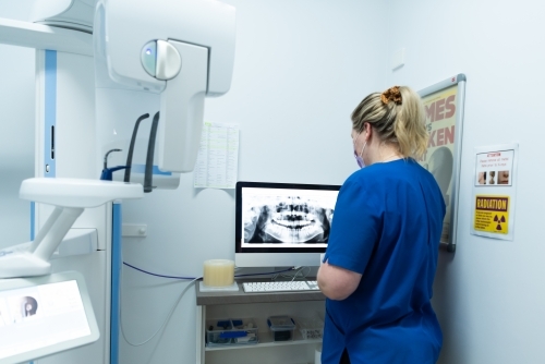 Female looking at teeth and jaw dental x-ray on monitor - Australian Stock Image