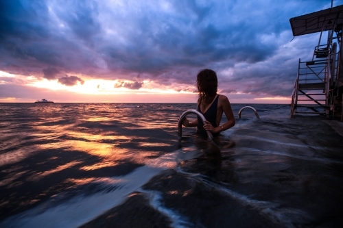 Female on pontoon in the ocean at Sunrise - Australian Stock Image