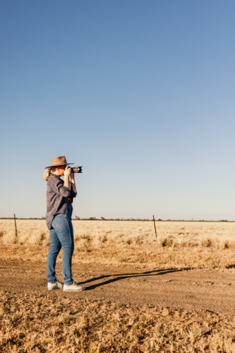 Female photographer using camera in paddock - Australian Stock Image