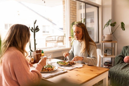 Female same sex couple eating a meal together at home - Australian Stock Image
