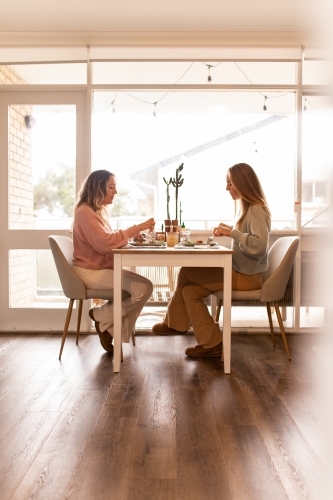 Female same sex couple eating a meal together at home - Australian Stock Image