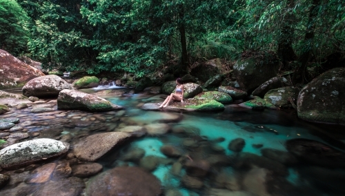 Female sitting on rock at Rainforest swimming hole