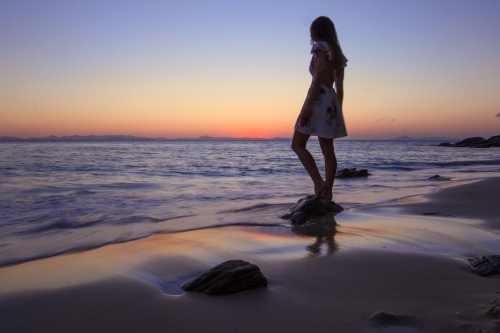 Female standing on Rock at the beach at Sunset - Australian Stock Image